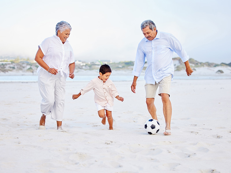 Happy family playing soccer on the beach